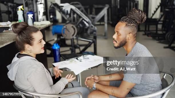 fitness instructor discussing training program with a client in gym - prop sporting position stock pictures, royalty-free photos & images