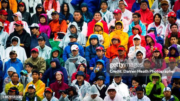 Japanese Formula One fans and spectators wearing multicoloured coats and anoraks in the rain while sat in a grandstand at the 2014 Japanese Grand...