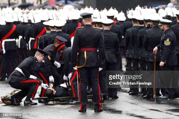 Royal Navy officer is helped by other members of the military after fainting during the Coronation of King Charles III and Queen Camilla on May 06,...