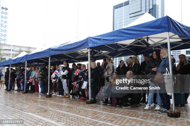 People take shelter from the rain as they watch the Coronation of King Charles III and Queen Camilla on a big screen in Centenary Square during the...