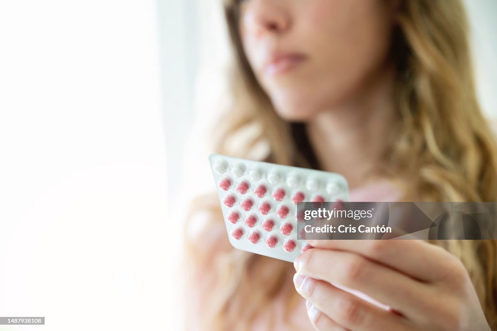 Woman holding contraceptive pill