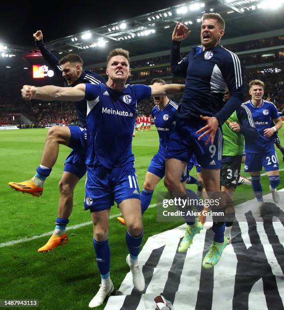 Marius Bulter of Schalke celebrates scoring his teams third goal of the game from the penalty spot with teammates during the Bundesliga match between...