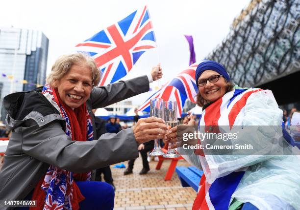 People raise a toast as they watch the Coronation of King Charles III and Queen Camilla on a big screen in Centenary Square during the Coronation of...