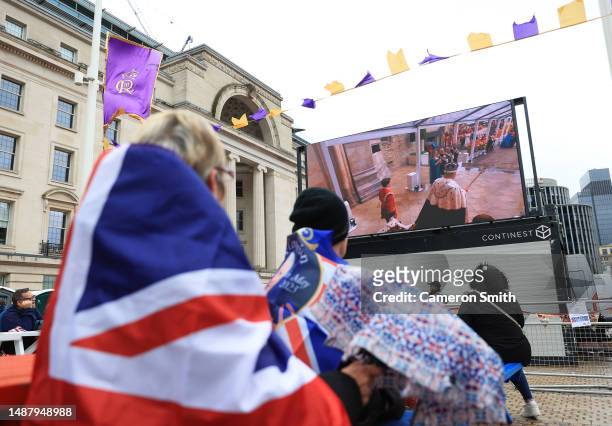 People watch the Coronation of King Charles III and Queen Camilla on a big screen in Centenary Square during the Coronation of King Charles III and...