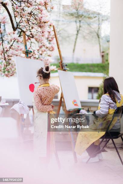 two girls with mental disabilities drawing a picture on the easel during the art psychotherapy - social awareness symbol stock pictures, royalty-free photos & images