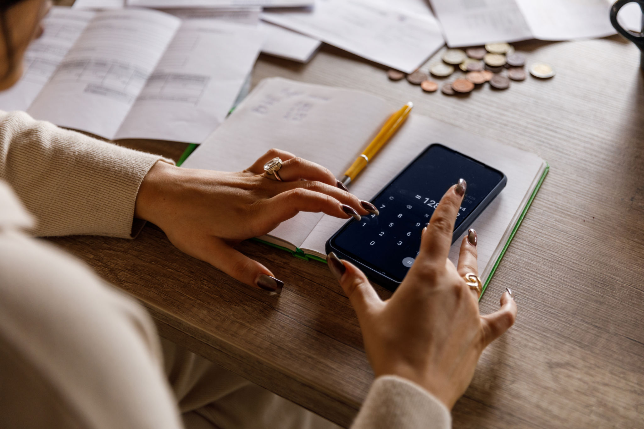 Young woman using a calculator app on her smart phone when sorting out finances at home Young woman using a calculator app on her smart phone when sorting out finances at home
