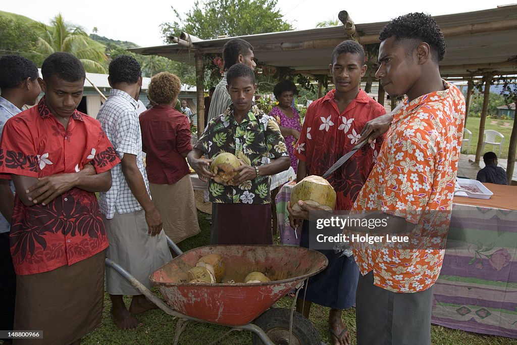 Men opening coconuts with machetes.