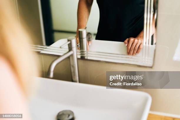 a woman washing her hands in the sink under the faucet - bulimie stock-fotos und bilder