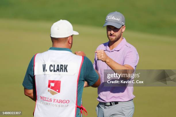 Wyndham Clark of the United States bumps fists with his caddie after finishing on the 18th green during the third round of the Wells Fargo...