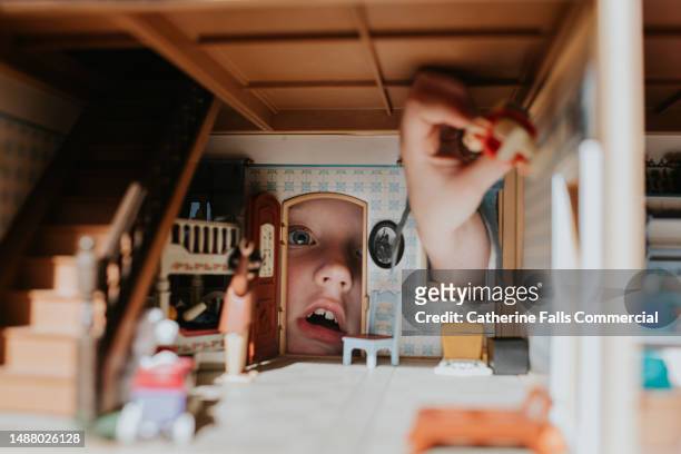 a little girl peering through the door of a dolls house - childs stock pictures, royalty-free photos & images