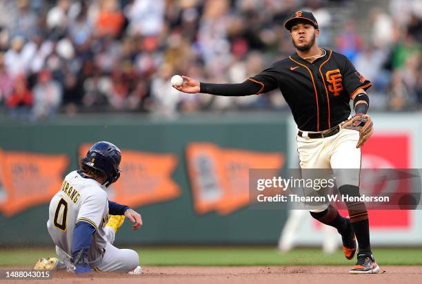 Thairo Estrada of the San Francisco Giants completes the double-play throwing to first base over the top of Pat Murphy of the Milwaukee Brewers in...