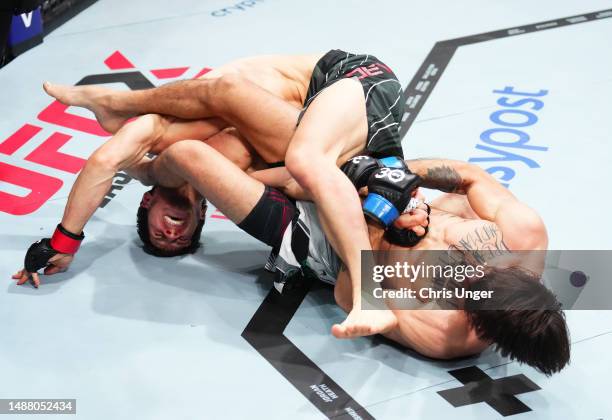 Diego Lopes of Brazil cranks an arm bar against Movsar Evloev of Russia in a featherweight fight during the UFC 288 event at Prudential Center on May...