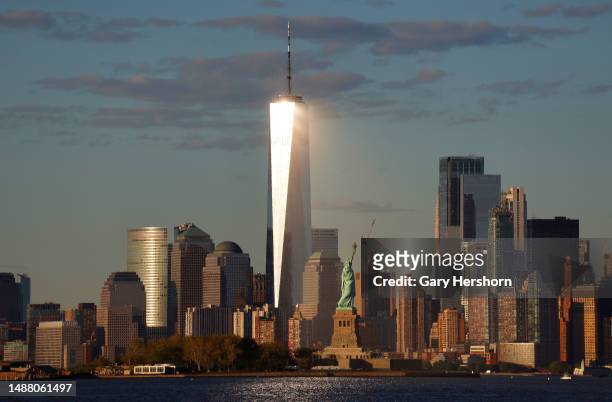 The setting sun reflects off the windows of One World Trade Center behind the Statue of Liberty in New York City on May 6 as seen from Jersey City,...