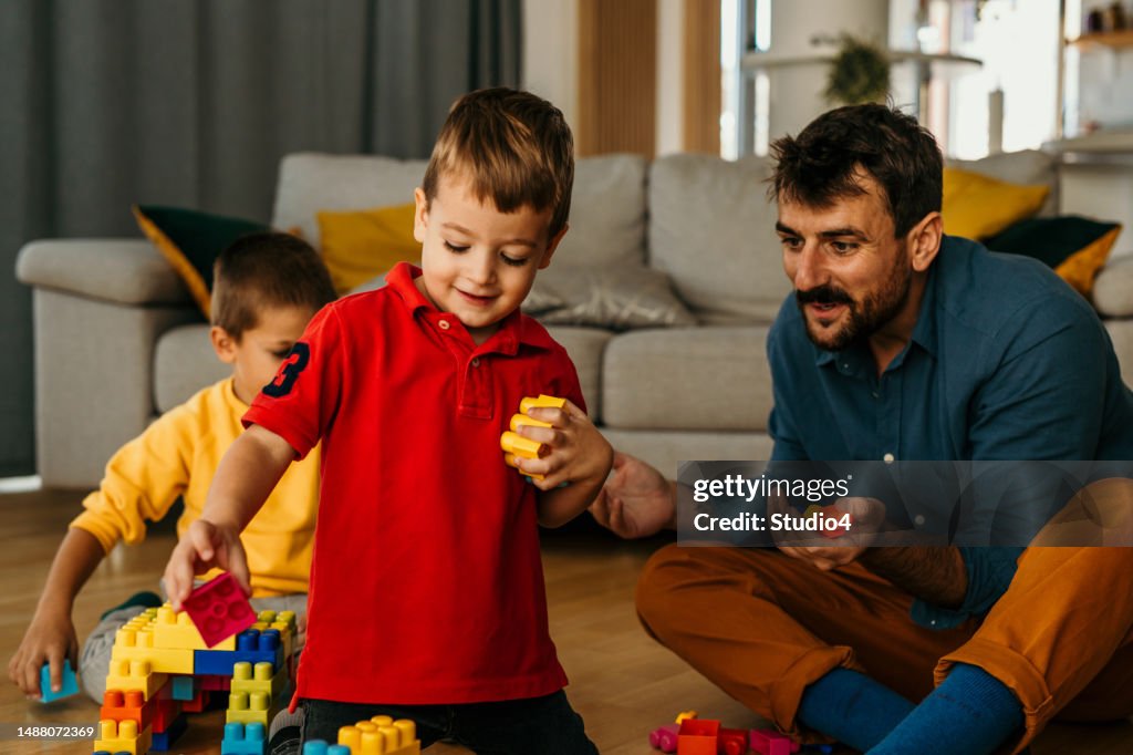 Father hugging and playing with his two sons at home.