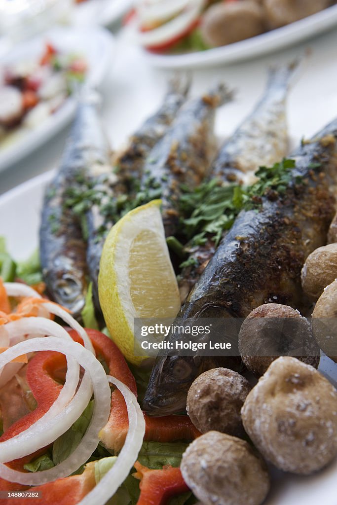 Grilled sardines with potatoes and salad at restaurant.