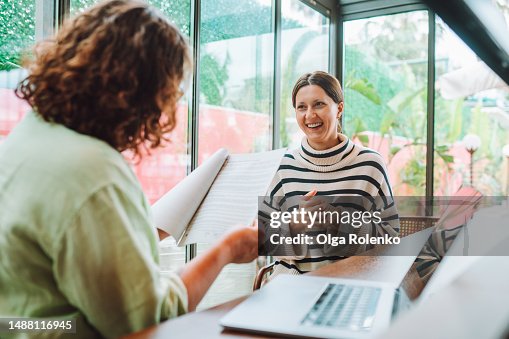 Rearview female recruitment reading and checking resume in hands interviewing and hiring woman candidate for joи near laptop in office with glass windows Rearview female recruitment reading and checking resume in hands interviewing and hiring woman candidate for joи near laptop in office with glass windows