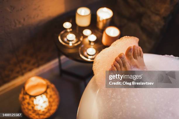 female feet in soap foam in bath tub. concept of pleasure and relaxation in spa. - candle photos et images de collection