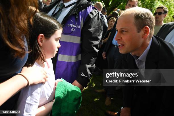 Prince William, Prince of Wales talks to a little girl named Lucy during a walkabout at The Big Lunch in Windsor, during the Coronation of King...