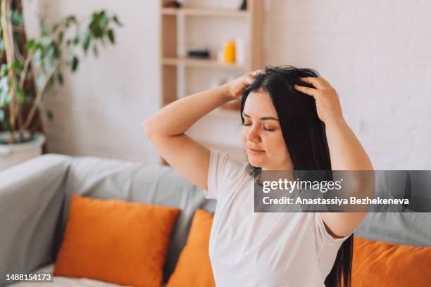 lady with black hair gives herself a scalp massage - head massage fotografías e imágenes de stock