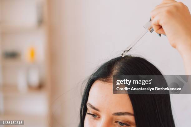 lady applying serum on scalp and hair from pipette - cuero cabelludo fotografías e imágenes de stock