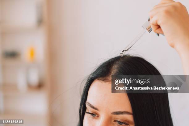 lady applying serum on scalp and hair from pipette - human scalp stock pictures, royalty-free photos & images