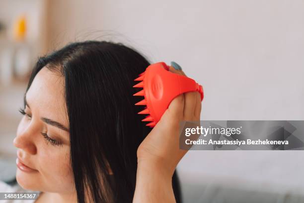 lady with scalp massager in her hands makes herself massage - brush in woman's hair imagens e fotografias de stock