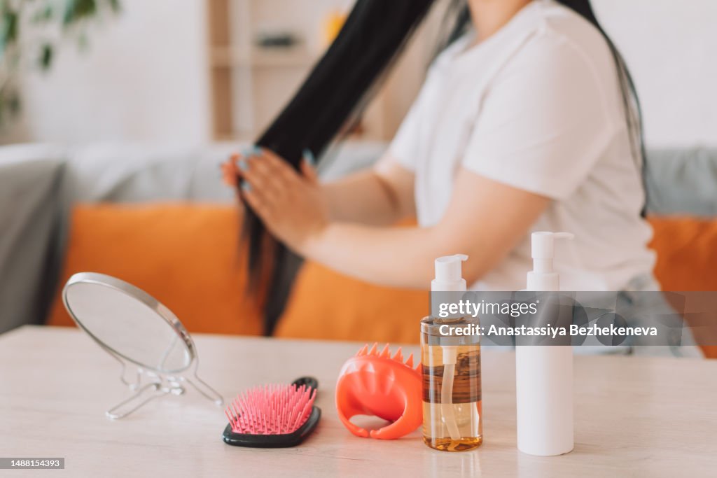 Lady applies oil to her black hair in front of cosmetics