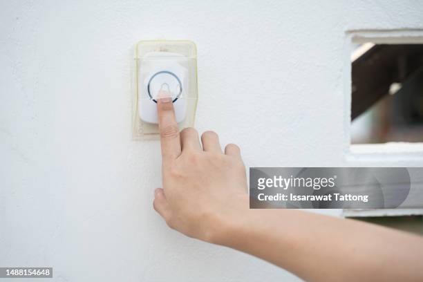 woman's hand uses a doorbell on the wall of the house - deurbel stockfoto's en -beelden