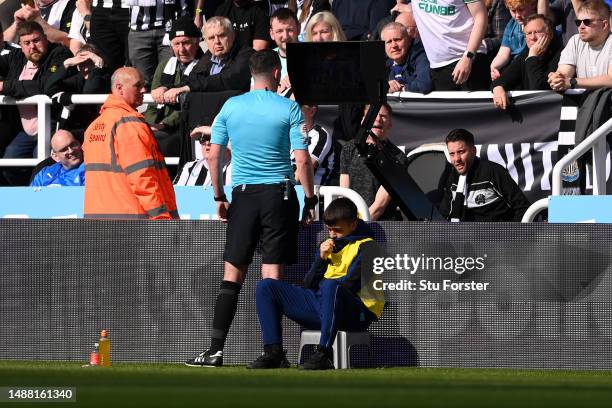 Referee Chris Kavanagh looks at a Monitor as they watch a VAR Review for a potential penalty after a handball incident, which is later ruled out,...