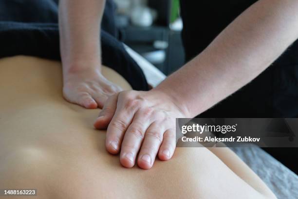 a doctor, a man, an osteopath, a rehabilitologist conducts physiological therapy with his hands. a masseur, a chiropractor does therapeutic massage to a patient, relieves muscle clamps and back pain. osteopathy session. alternative medicine. health care. - shiatsu stock pictures, royalty-free photos & images
