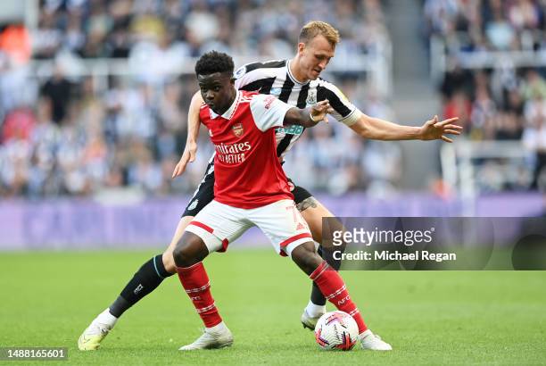 Bukayo Saka of Arsenal is challenged by Dan Burn of Newcastle United during the Premier League match between Newcastle United and Arsenal FC at St....