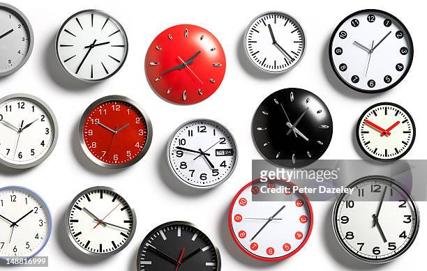 a selection of wall clocks showing different times - primo turno foto e immagini stock