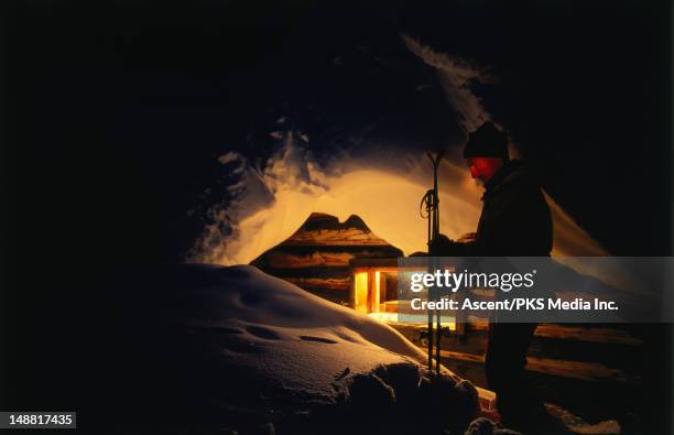 skiier standing outside hut. - night skiing stock pictures, royalty-free photos & images