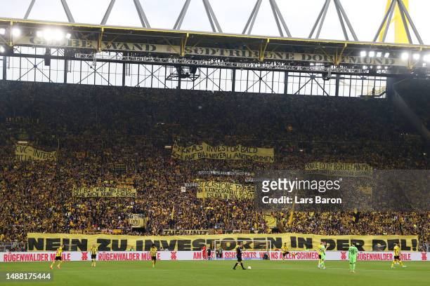 Fans hold banners in protest against private equity during the Bundesliga match between Borussia Dortmund and VfL Wolfsburg at Signal Iduna Park on...