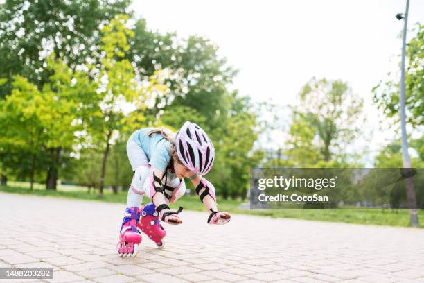 sechsjähriges mädchen auf rollschuhen im park fällt auf den boden - skate fail stock-fotos und bilder