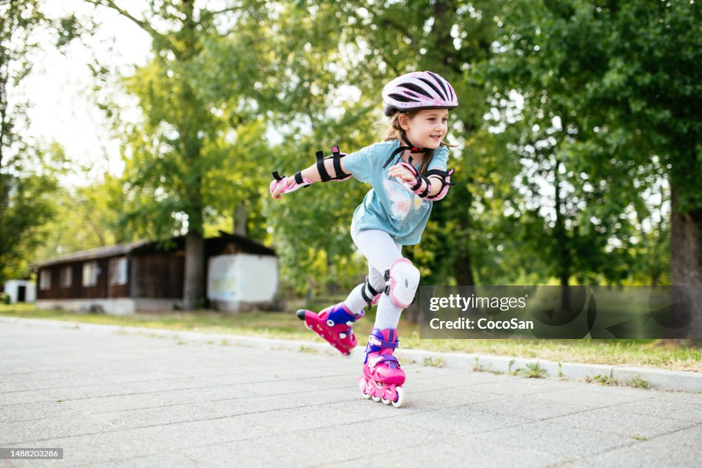 Six year old smiling girl on roller skates in park