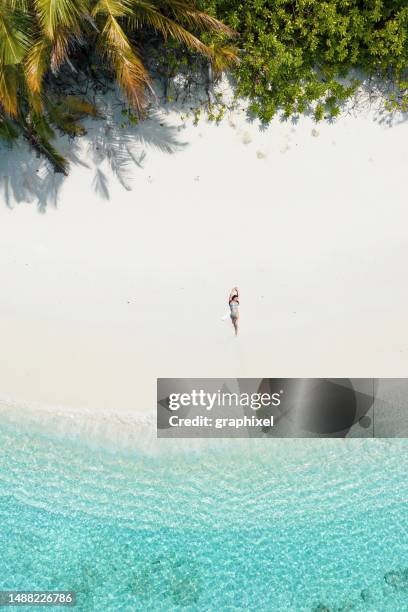 luftaufnahme einer frau, die an einem sandstrand liegt - einsame insel stock-fotos und bilder
