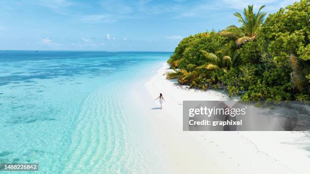 vista aérea con dron de una mujer caminando en una isla desierta en maldivas - maldivas fotografías e imágenes de stock