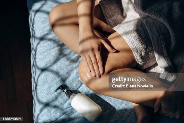 skin and body care woman hands applies moisturizing lotion to her legs and thighs after showering or a protective product after tanning shadow overlay - leg stock pictures, royalty-free photos & images