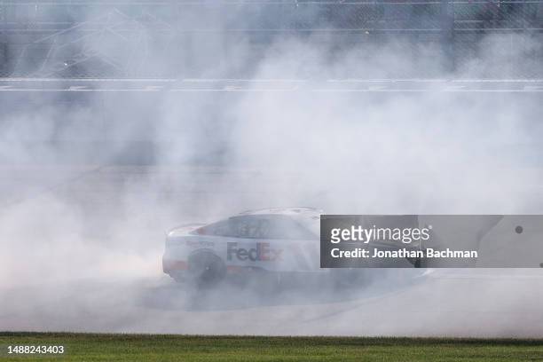 Denny Hamlin, driver of the FedEx Express Toyota, celebrates with a burnout after winning the NASCAR Cup Series Advent Health 400 at Kansas Speedway...