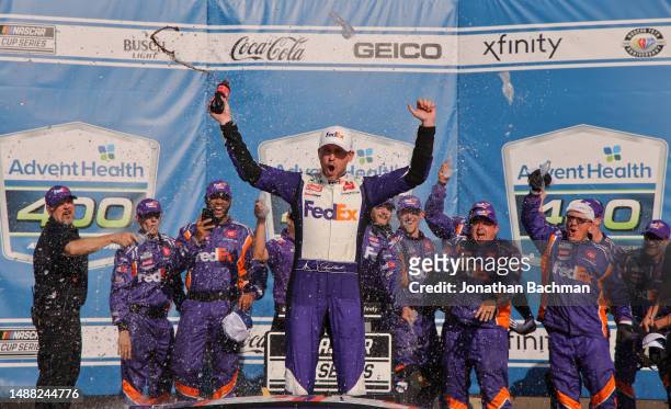 Denny Hamlin, driver of the FedEx Express Toyota, celebrates in victory lane after winning the NASCAR Cup Series Advent Health 400 at Kansas Speedway...