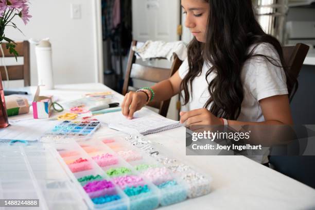 a 12-14 year old girl inside her home is making bracelets to sell to raise funds - bracelet making stock pictures, royalty-free photos & images