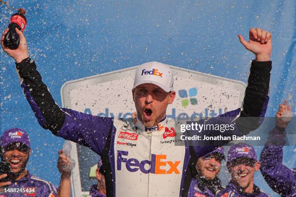 Denny Hamlin, driver of the FedEx Express Toyota, celebrates in victory lane after winning the NASCAR Cup Series Advent Health 400 at Kansas Speedway...