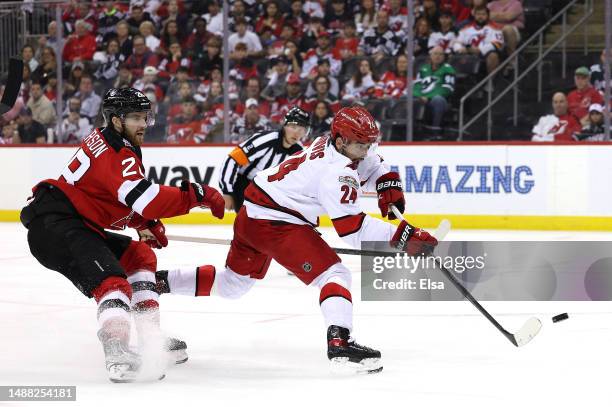 Seth Jarvis of the Carolina Hurricanes scores a goal with this shot as Damon Severson of the New Jersey Devils defends during the third period in...