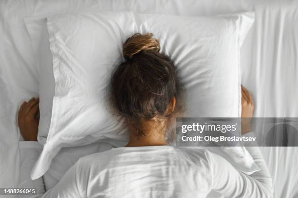 woman in depression crying in pillow. top view from the back. crisis or bad news concept - midlife crisis stock pictures, royalty-free photos & images