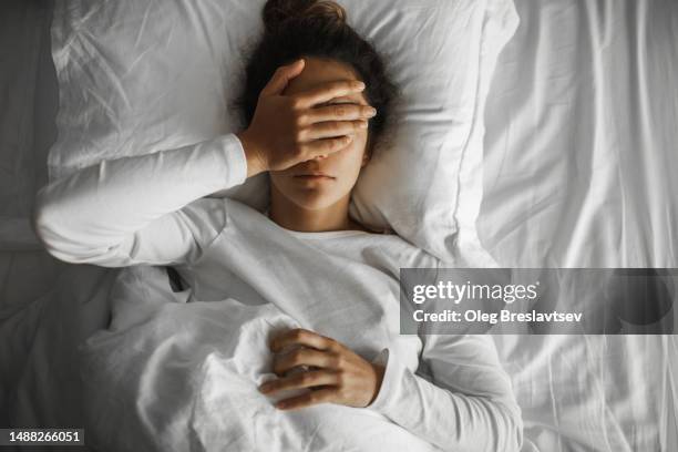woman lying down in bed and crying with closed face. relationship breakup and stress - midlife crisis stock pictures, royalty-free photos & images