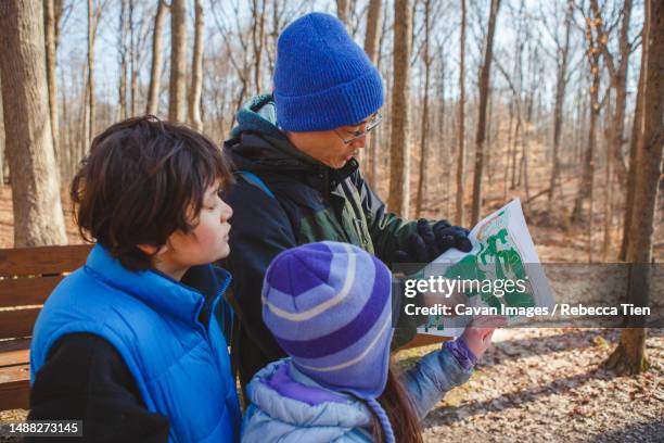 a father and children stand in forest in winter looking at map - columbus ohio map stock pictures, royalty-free photos & images