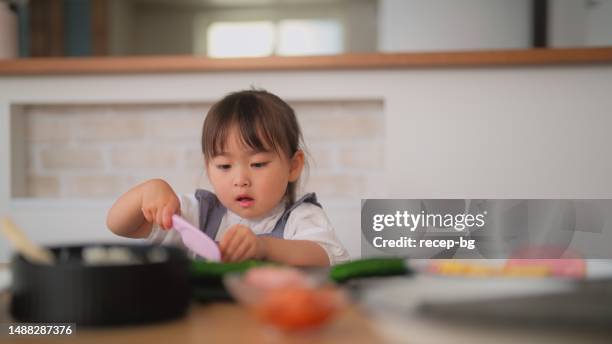 mother and daughter preparing and eating sushi at home - hand roll stock pictures, royalty-free photos & images