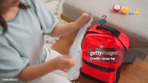 mujer preparando bolsa de emergencia en casa - mochila-bolsa fotografías e imágenes de stock