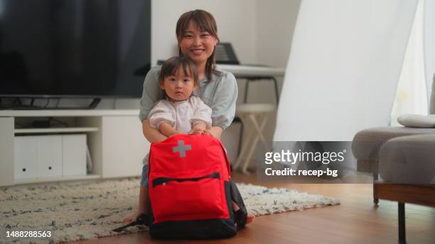 portrait of happy mother and small daughter preparing emergency bag at home - safety kit imagens e fotografias de stock